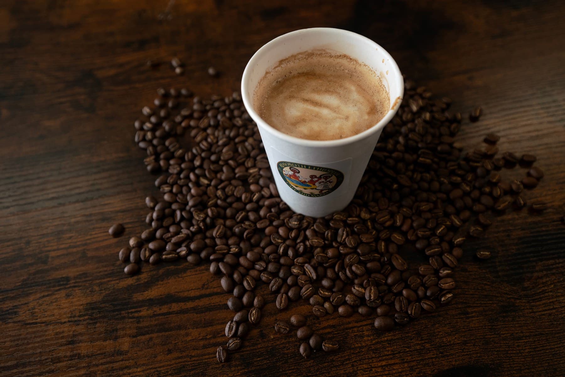 Buna House latte and roasted beans photographed on a warm wooden tabletop